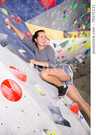 Young sporty woman training at bouldering gym without special climbing equipment Young sporty woman training at bouldering gym without special climbing equipment 76035231