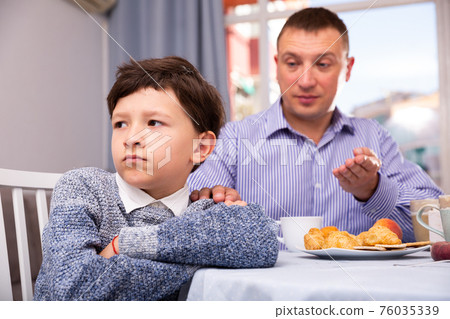 Upset father and offended son arguing in domestic interior Upset father and offended son arguing in domestic interior 76035339