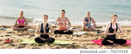 Sporty females meditating in yoga position Padmasana on seaside Sporty females meditating in yoga position Padmasana on seaside 76035439