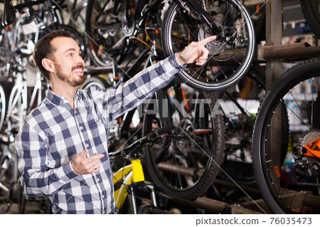 Man in sports workshop mounts bike using special tools Man in sports workshop mounts bike using special tools 76035473