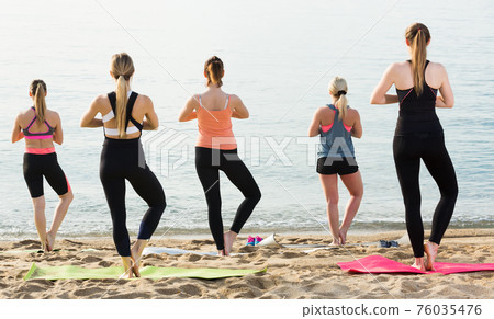 Back view of young females training yoga positions Back view of young females training yoga positions 76035476