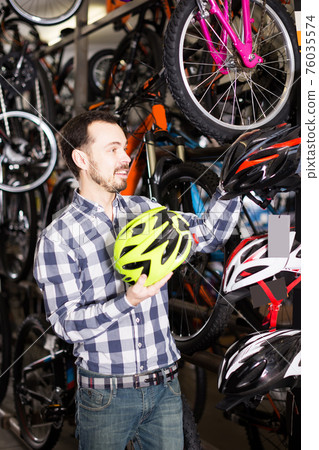 Man selects a good helmet for cycling Man selects a good helmet for cycling 76035574