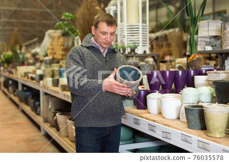 Male seller is standing near clay pots in stock 76035578