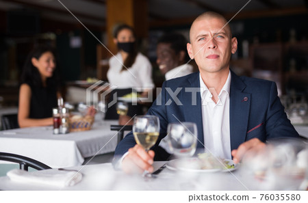 adult man thinking and eating in modern cafe 76035580