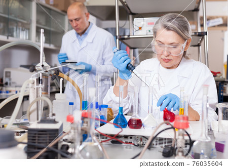 Female chemist mixing chemical agents Female chemist mixing chemical agents 76035604