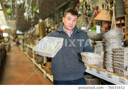 Puzzled man choosing wickerwork in shop 76035652
