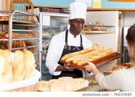 Baker serving female customer Baker serving female customer 76035695