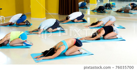 Men and women exercising yoga poses 76035700
