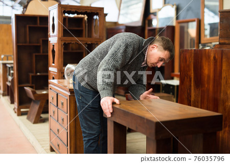 Man chooses new furniture for home in the store Man chooses new furniture for home in the store 76035796