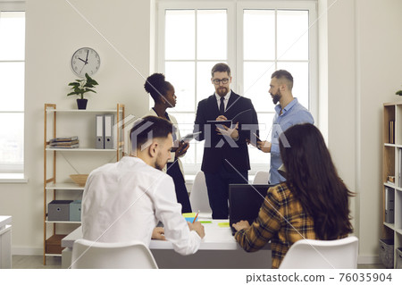 Multiethnic group of employees and team leader working in busy open space office Multiethnic group of employees and team leader working in busy open space office 76035904