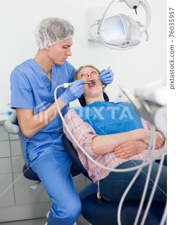 Male dentist treating young female patient in dental office Male dentist treating young female patient in dental office 76035957