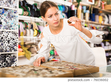 Woman choosing buttons in shop 76036002