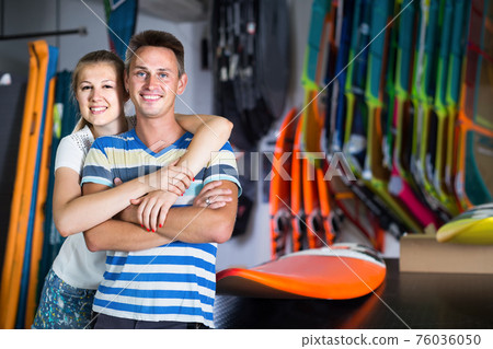 Young couple is posing in surfboard store on the beach. Young couple is posing in surfboard store on the beach. 76036050