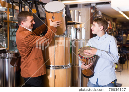 Father and teenage son examining drum units in guitar shop Father and teenage son examining drum units in guitar shop 76036127