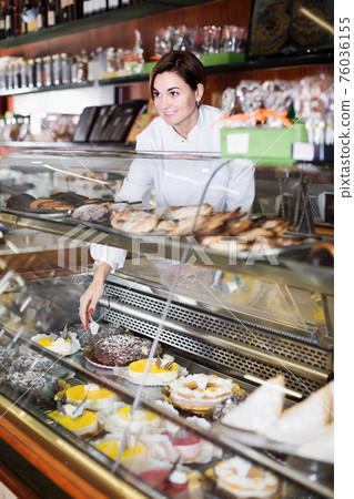 Woman assistance showing best dessert to choose 76036155