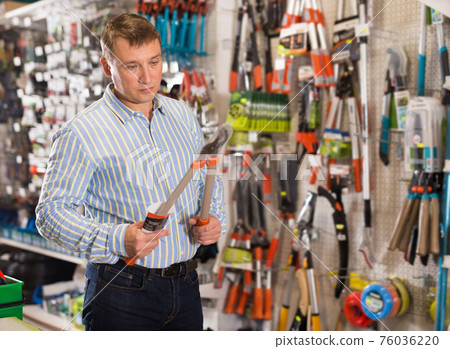 Man choosing new secateurs in garden equipment shop Man choosing new secateurs in garden equipment shop 76036220