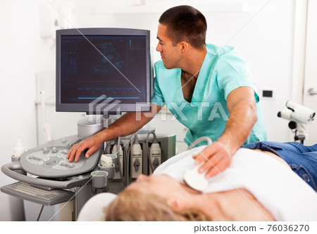 Positive male doctor diagnosing female patient using modern ultrasound scanner in private clinic Positive male doctor diagnosing female patient using modern ultrasound scanner in private clinic 76036270