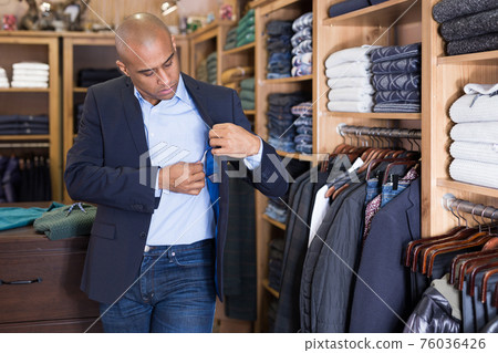 Man choosing suit jacket in clothing store Man choosing suit jacket in clothing store 76036426