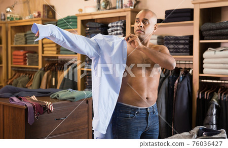 Man trying on shirt in clothing store Man trying on shirt in clothing store 76036427