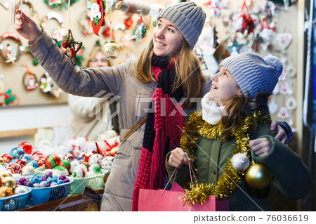 Young girl and her mother are choosing Christmas decorations 76036619