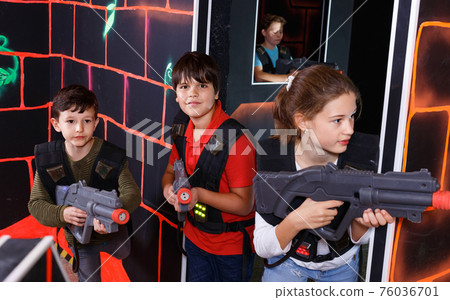 Group of happy teenagers with laser guns having fun on dark lasertag arena Group of happy teenagers with laser guns having fun on dark lasertag arena 76036701