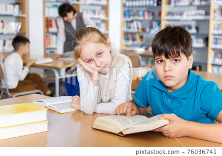 Tired girl and boy in school library Tired girl and boy in school library 76036741