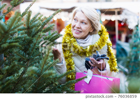 Mature female buying decoration and tree at Christmas Fair 76036859