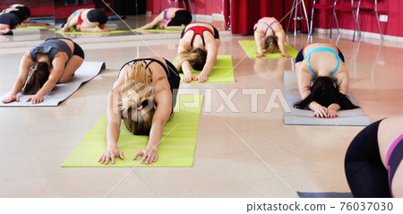 Women exercising yoga poses in fitness center Women exercising yoga poses in fitness center 76037030