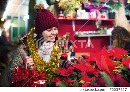 Girl buying floral compositions at Christmas market Girl buying floral compositions at Christmas market 76037237