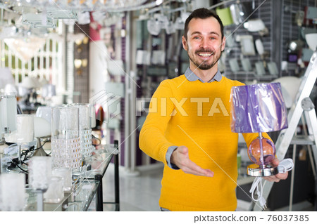 Male in lighter shop is choosing stylish and modern lamp Male in lighter shop is choosing stylish and modern lamp 76037385