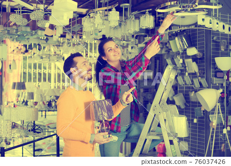 Man and girl choosing modern chandelier Man and girl choosing modern chandelier 76037426