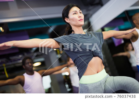 Woman with others doing step aerobics in fitness club Woman with others doing step aerobics in fitness club 76037438
