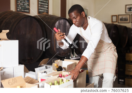 Winemaker inspecting wine bottles in store Winemaker inspecting wine bottles in store 76037625