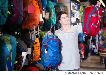 Woman selects a tourist rucksack Woman selects a tourist rucksack 76037671