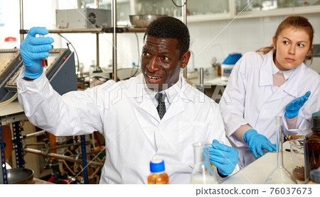 Male scientist with test tubes checking for result of chemical experiment 76037673