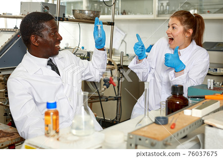 Male and female scientists looking for result after chemical experiment Male and female scientists looking for result after chemical experiment 76037675