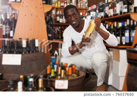 Afro man choosing bottle of wine 76037680