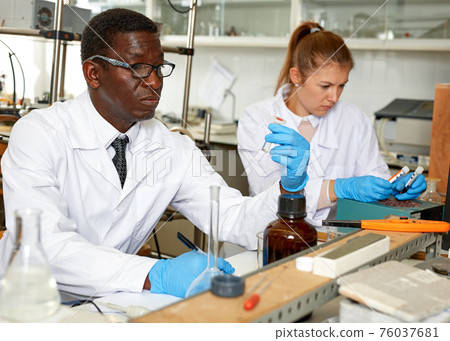 Serious man lab scientist in glasses working with reagents and test tubes Serious man lab scientist in glasses working with reagents and test tubes 76037681
