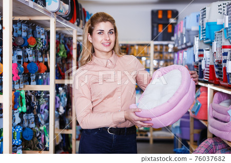 saleswoman showing sleeping place for pet saleswoman showing sleeping place for pet 76037682