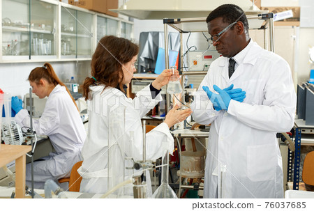Serious man and woman lab technicians discussing about results of experiments Serious man and woman lab technicians discussing about results of experiments 76037685