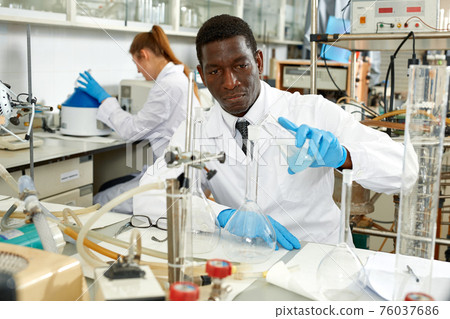 Serious male scientists with glass test tubes during chemical experiment Serious male scientists with glass test tubes during chemical experiment 76037686