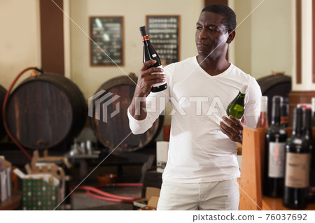 Afro man choosing bottle of wine Afro man choosing bottle of wine 76037692