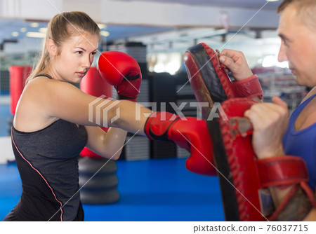 man is training with woman and punching gloves in box gym. man is training with woman and punching gloves in box gym. 76037715