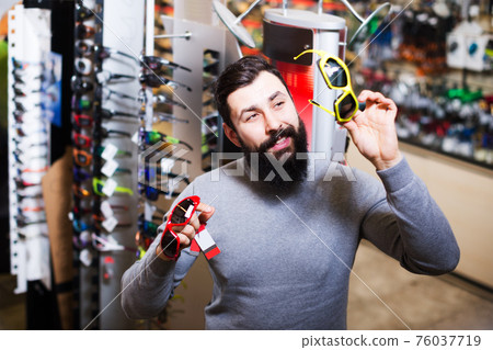 Guy deciding on new sunglasses 76037719
