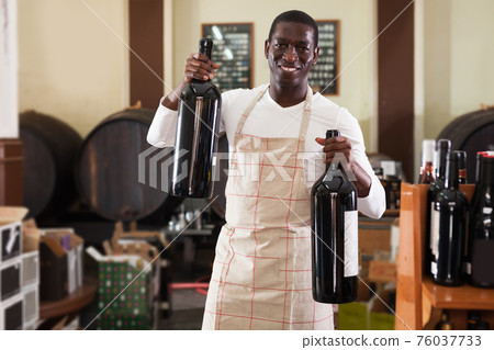 afro male seller of wine shop offering wine bottle to buy afro male seller of wine shop offering wine bottle to buy 76037733
