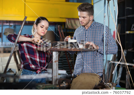 Portrait of man with young woman who are working together in workshop. Portrait of man with young woman who are working together in workshop. 76037792
