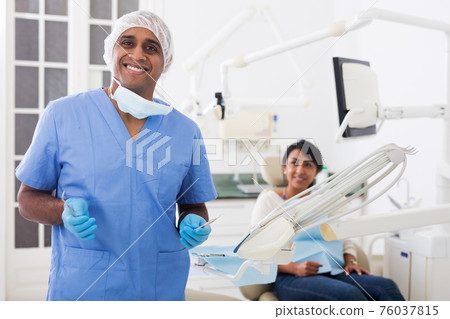 Smiling qualified stomatologist posing at dental office 76037815