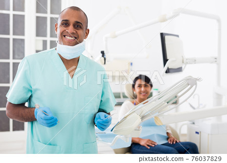 Smiling qualified stomatologist posing at dental office 76037829