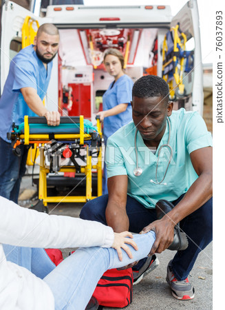 Ambulance team helping injured woman 76037893