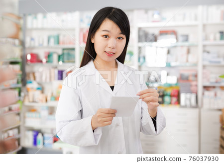 Chinese female is checking medicine with notebook in pharmacy 76037930